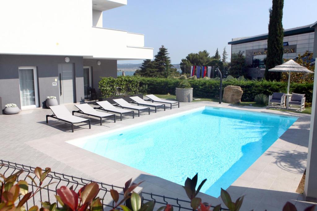 a swimming pool with lounge chairs next to a building at Casa Del Sole Portoroz in Portorož
