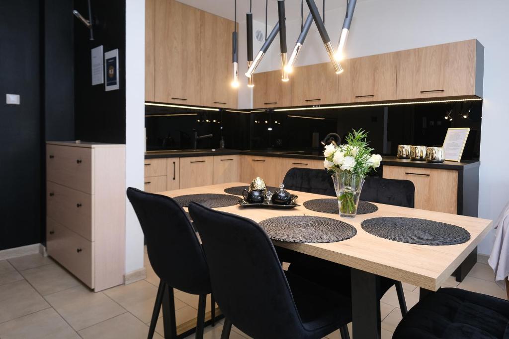 cocina con mesa de madera y sillas negras en Apartamenty Jasny Brzeg, en Władysławowo