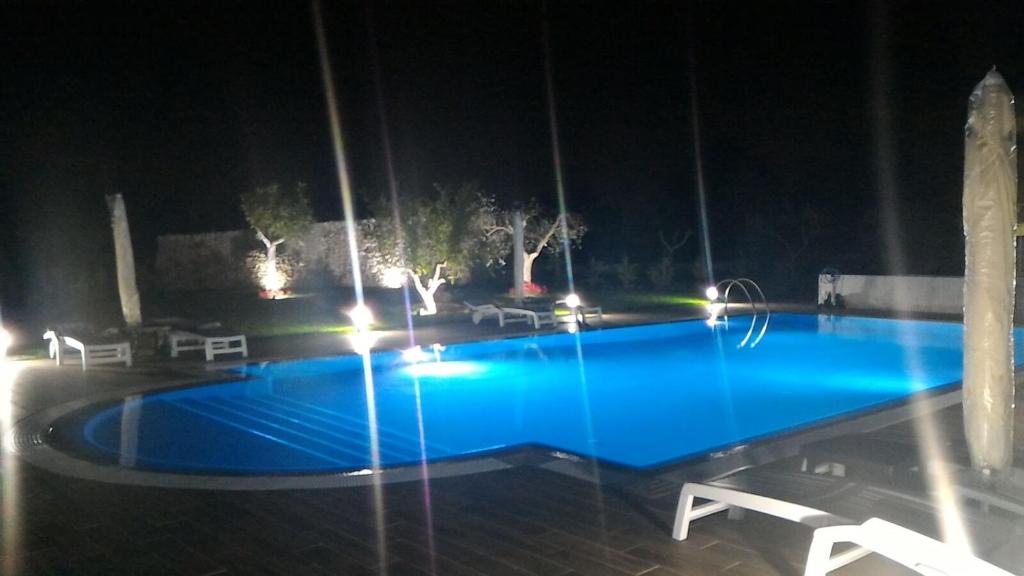 ein großer blauer Pool in der Nacht mit Lichtern in der Unterkunft Casolare 67 in Noci