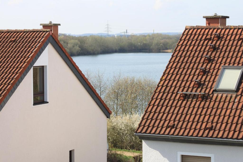 a white house with a red roof and a lake at B&B am See Köln - Privatzimmer in Cologne