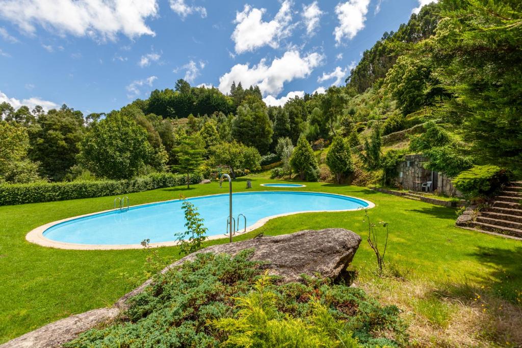 uma piscina num campo relvado com uma montanha em Casa Nogueira - Minho's Guest em Pousadouros