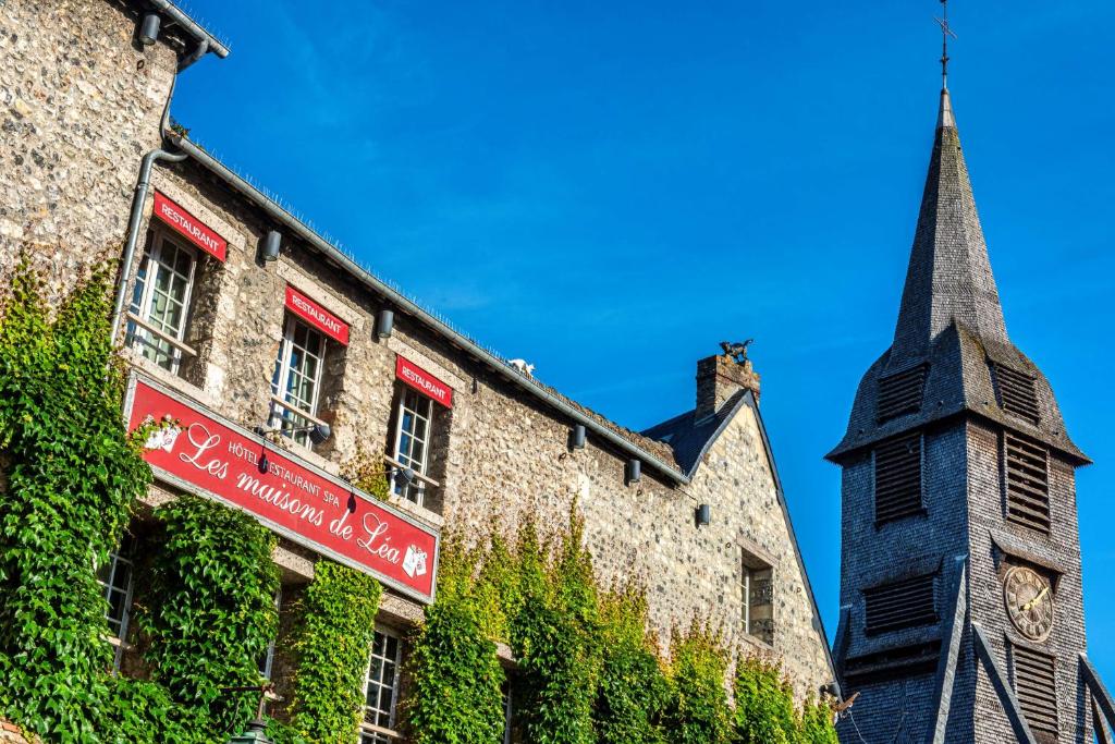 um edifício com uma torre de relógio ao lado de uma igreja em Les Maisons de Lea, a member of Radisson Individuals em Honfleur