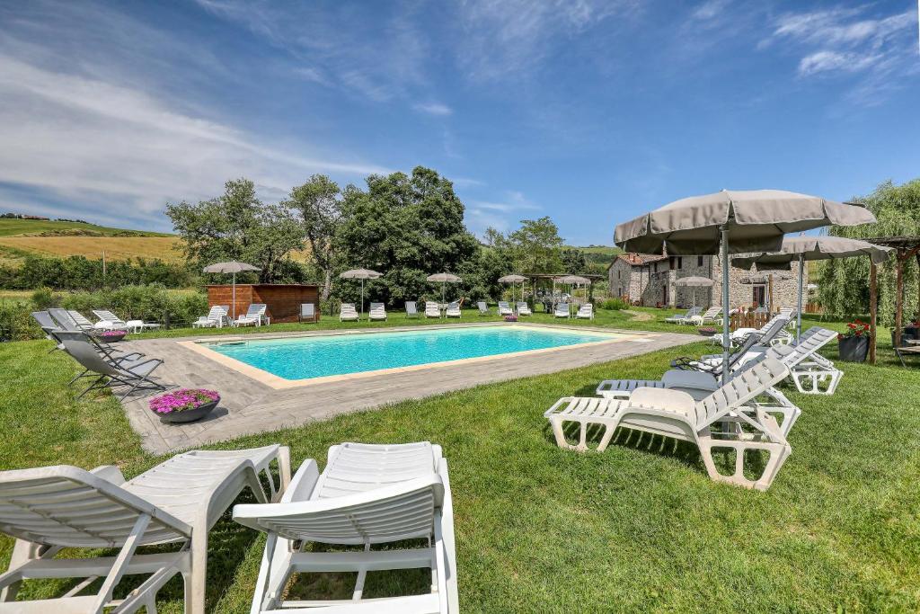 grupa białych krzeseł i basen w obiekcie Agriturismo Podere San Giorgio w mieście Radicofani