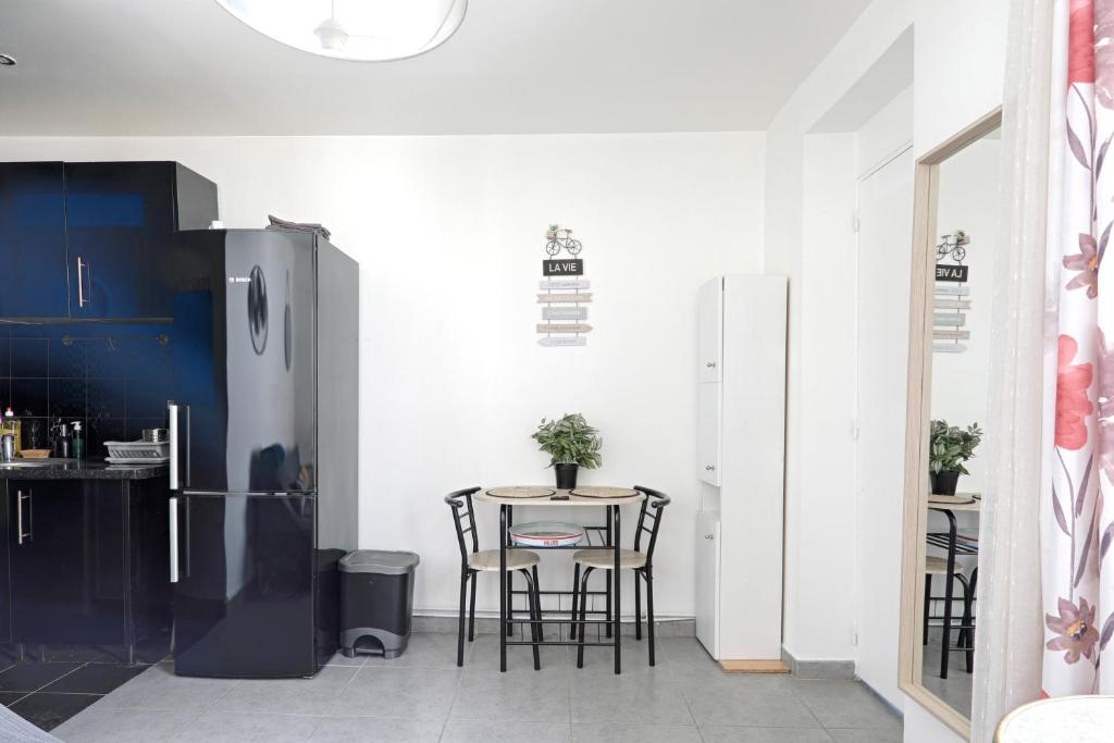 a kitchen with a table with chairs and a refrigerator at On Stage - Appartement pour 3 personnes in Ivry-sur-Seine
