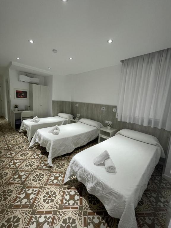 a hotel room with three beds in it at Hostal Nova Barcelona in Barcelona