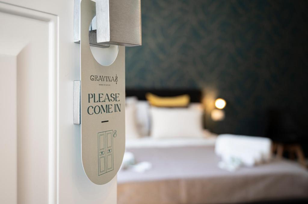 un cartello su una porta con un letto in una stanza di Gravina8 - Rooms in Naples a Napoli