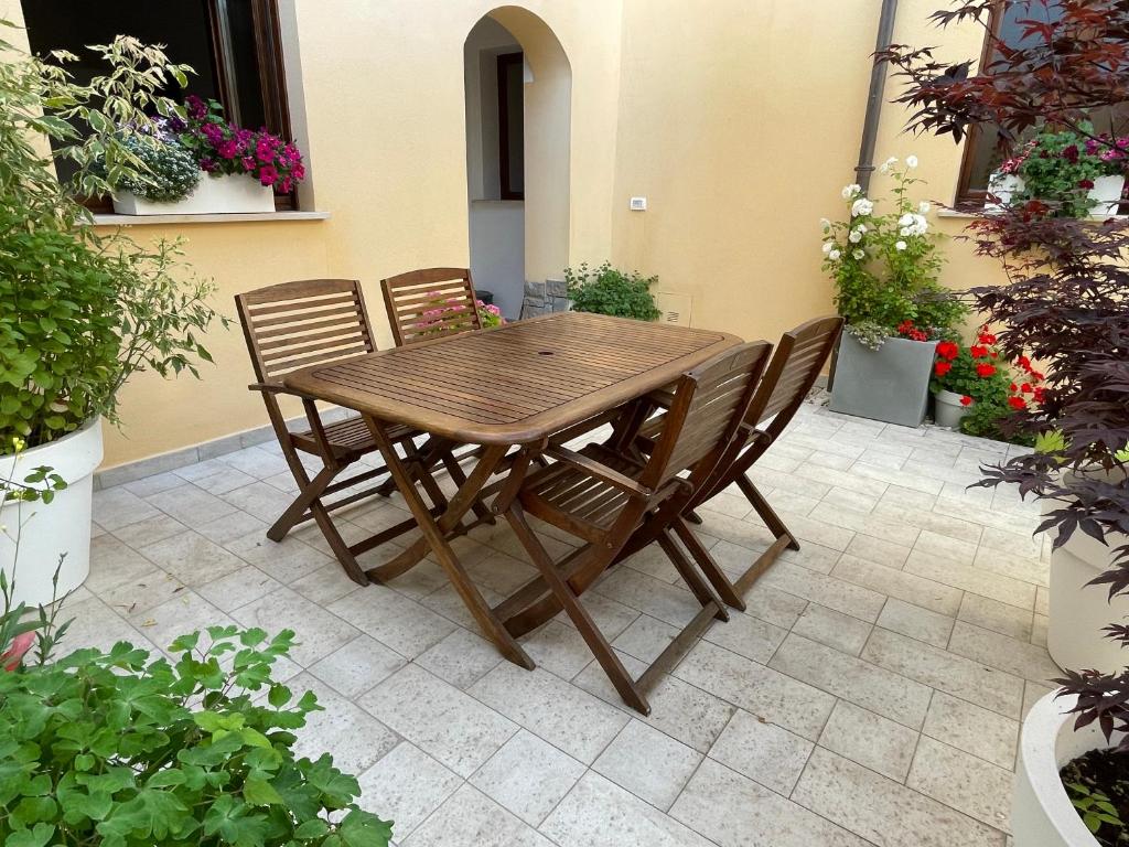 une table et des chaises en bois sur une terrasse fleurie dans l'établissement La Pulchella, à LʼAquila