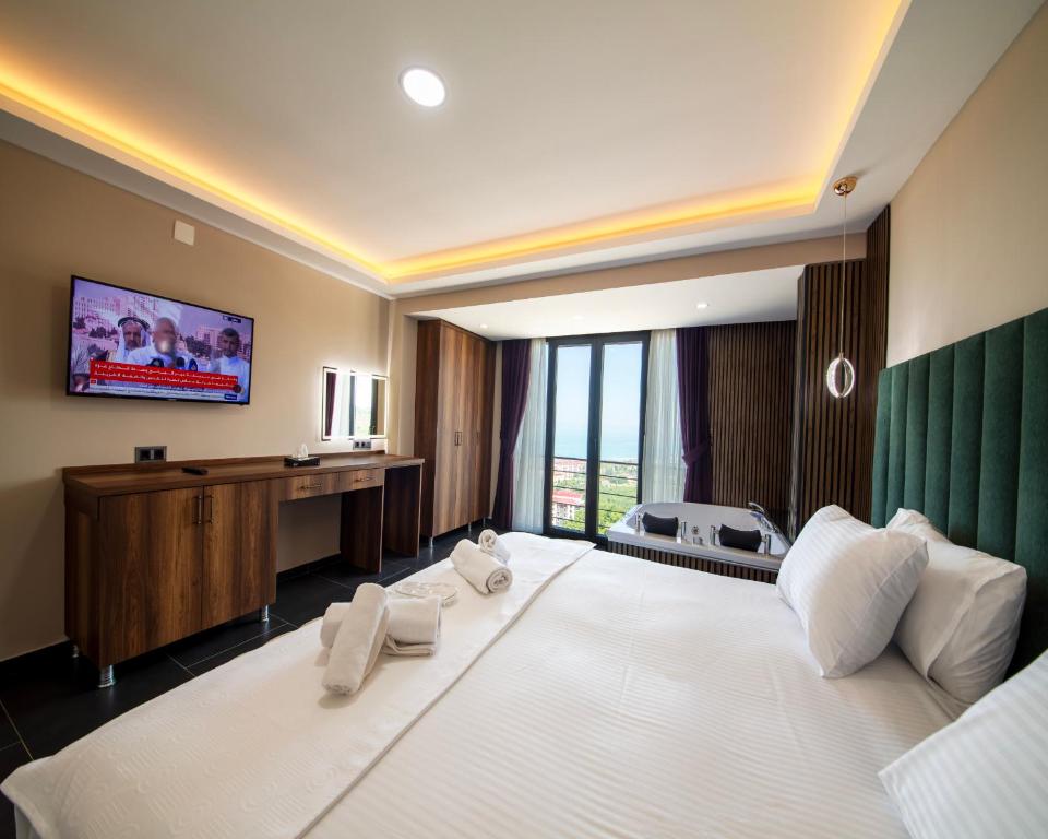 een slaapkamer met een groot wit bed en een televisie bij Royal Villa in Trabzon
