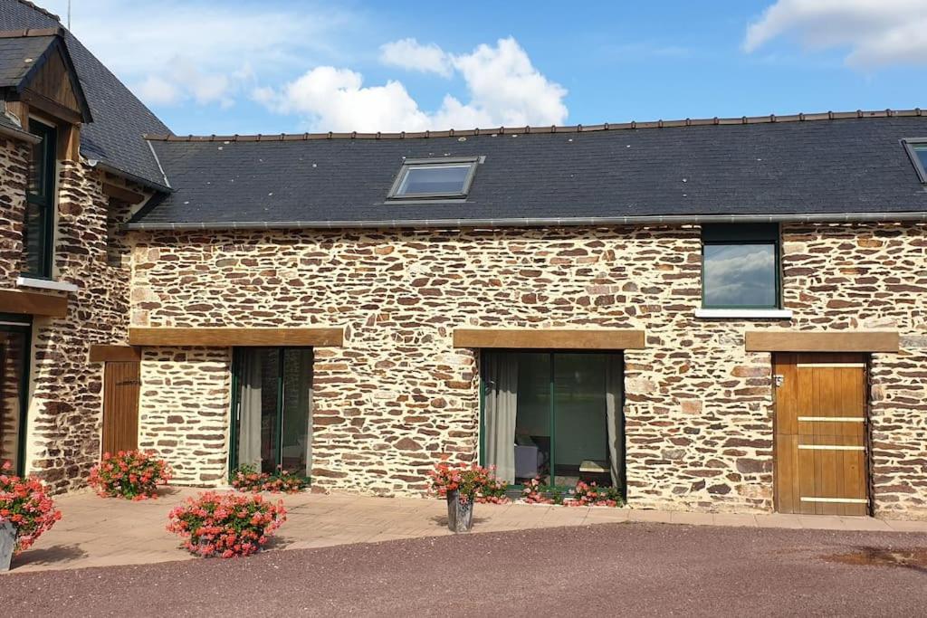 - un bâtiment en pierre avec deux portes et des fleurs dans l'établissement La grange de Merlin, à Concoret