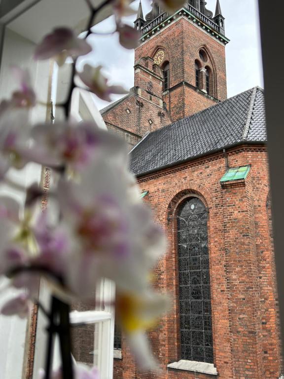 a brick church with a clock tower with pink flowers at KøbenhavnK in Copenhagen