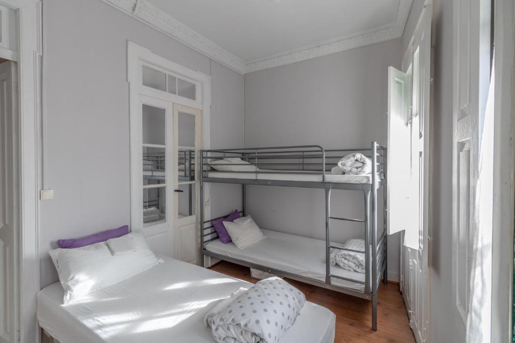 a white room with a bunk bed and a bed and a couch at Albergue Casa de Abreu in Redondela