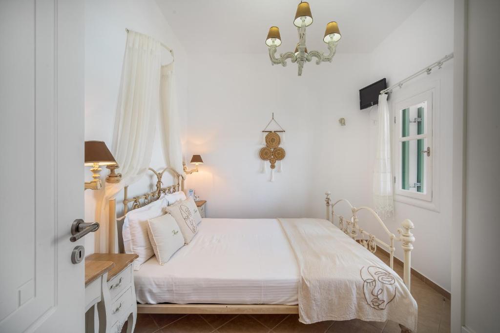 a white bedroom with a bed and a chandelier at Astrio Suites in Livadi