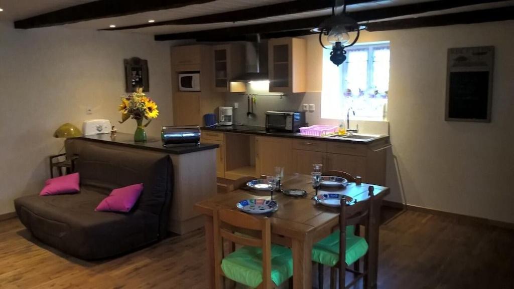 a living room with a table and a kitchen at Maison de campagne in Sénergues