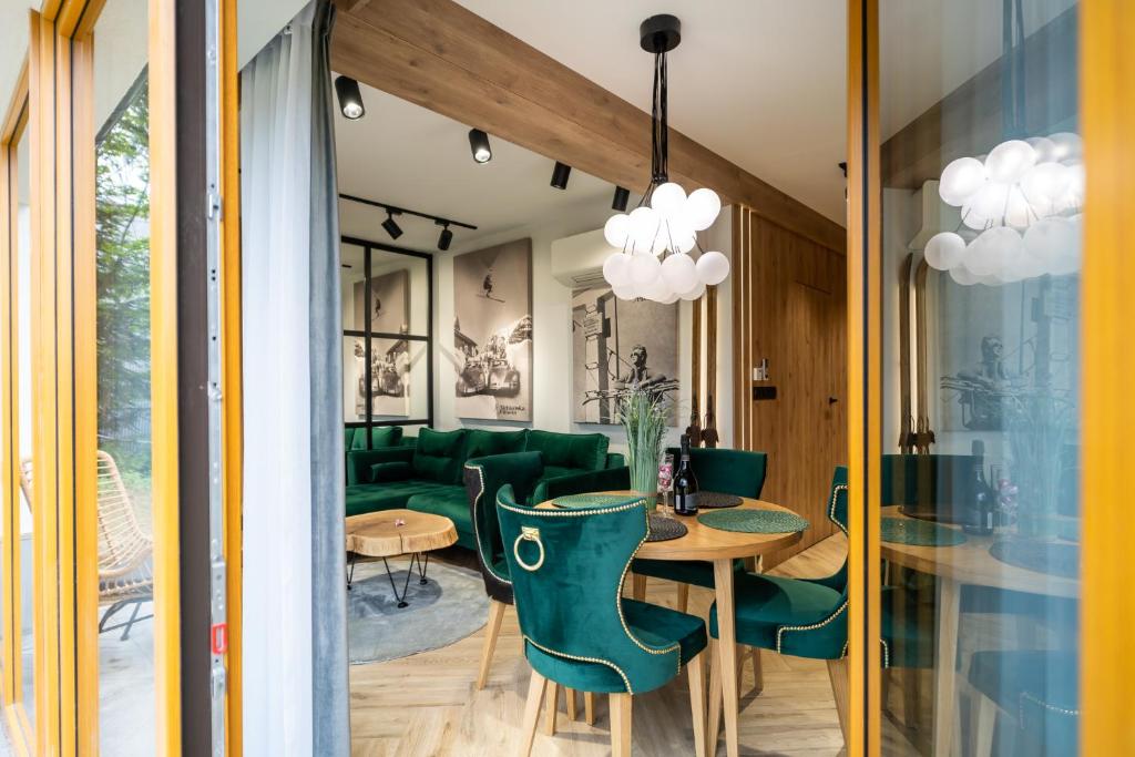 a dining room with a table and green chairs at Apartament Niebiańska Polana by Apart Concept Podhale in Kościelisko