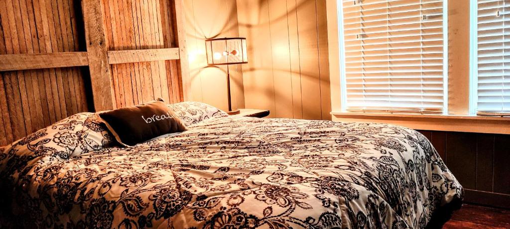 a bedroom with a bed and a lamp and a window at Hocking Hills Rusty Lofts in Logan