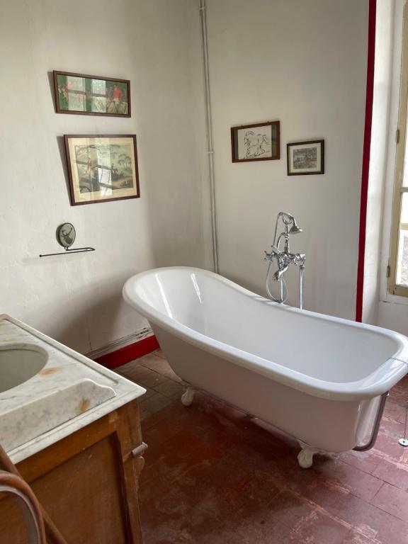 une baignoire blanche dans une salle de bain avec un lavabo dans l'établissement La Maison du meunier, à Romorantin-Lanthenay