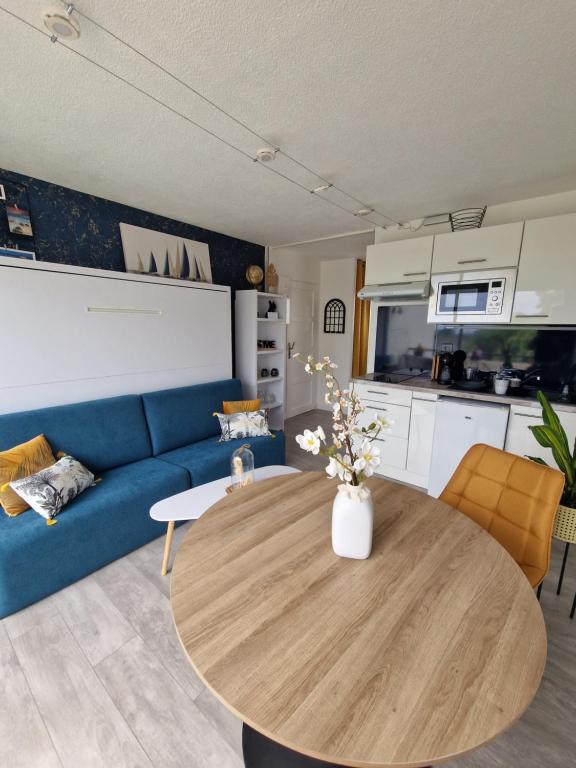un salon avec une table et un canapé bleu dans l'établissement GUIDEL-PLAGES Studio Lumineux Balcon Vue Mer & Piscine, à Guidel