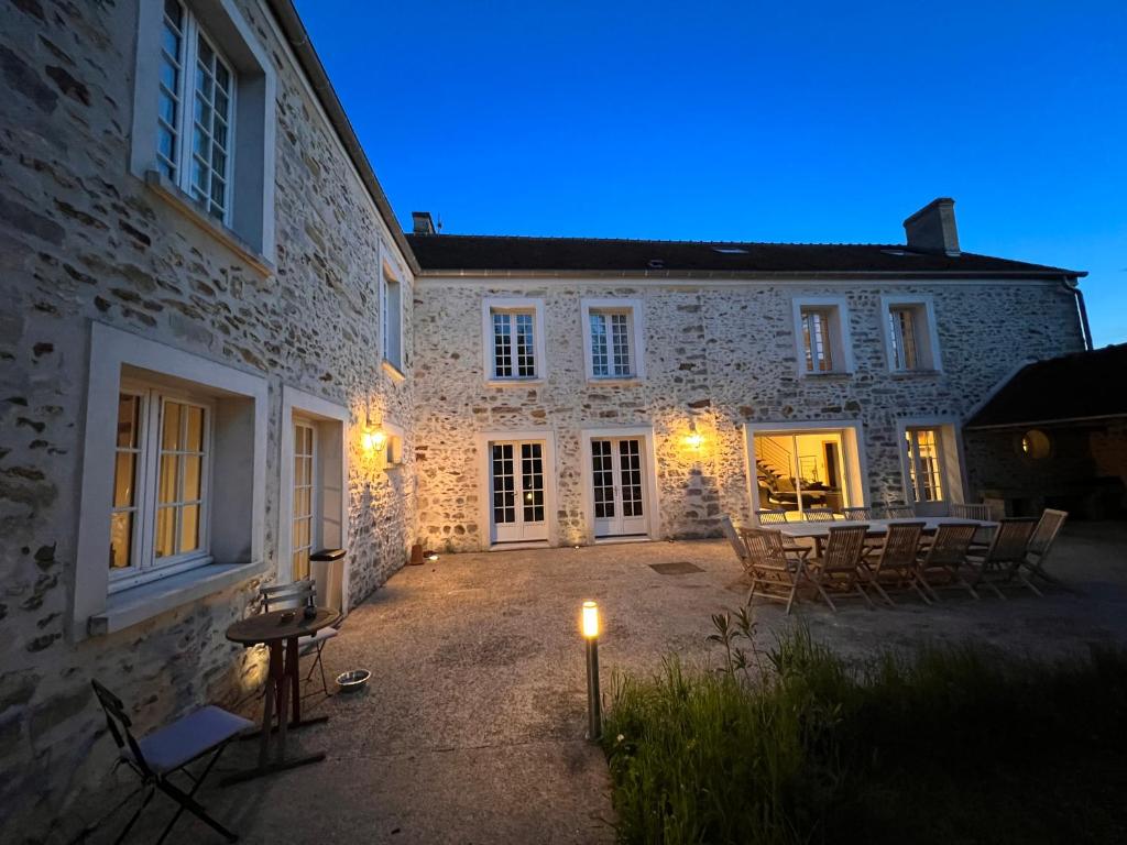 a lit up courtyard of a stone building with chairs at Le domaine de Jade in Châtillon-la-Borde