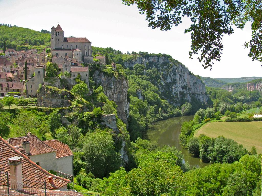 a town on a hill with a river and a castle at Gîte "le haut des Poujades" in Reilhaguet