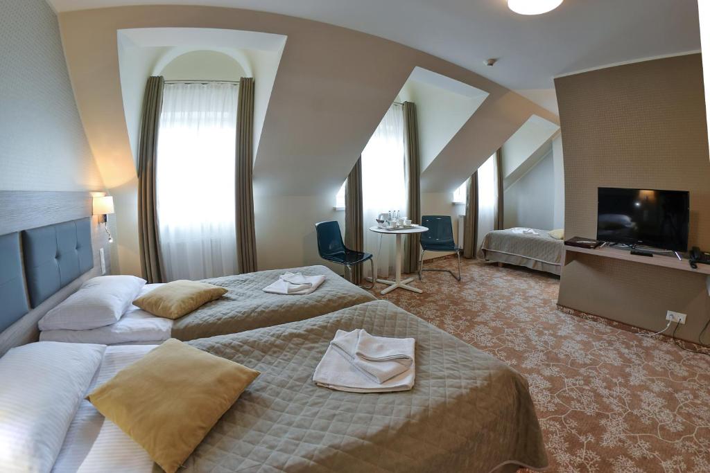 a hotel room with two beds and a flat screen tv at Hotel Panorama Nowy Sącz in Nowy Sącz
