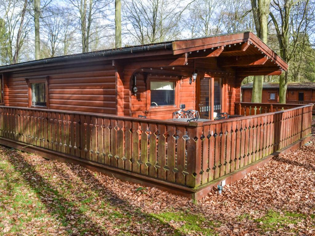 a log cabin in the woods with a wooden fence at Larch Lodge - Uk37187 in Legbourne