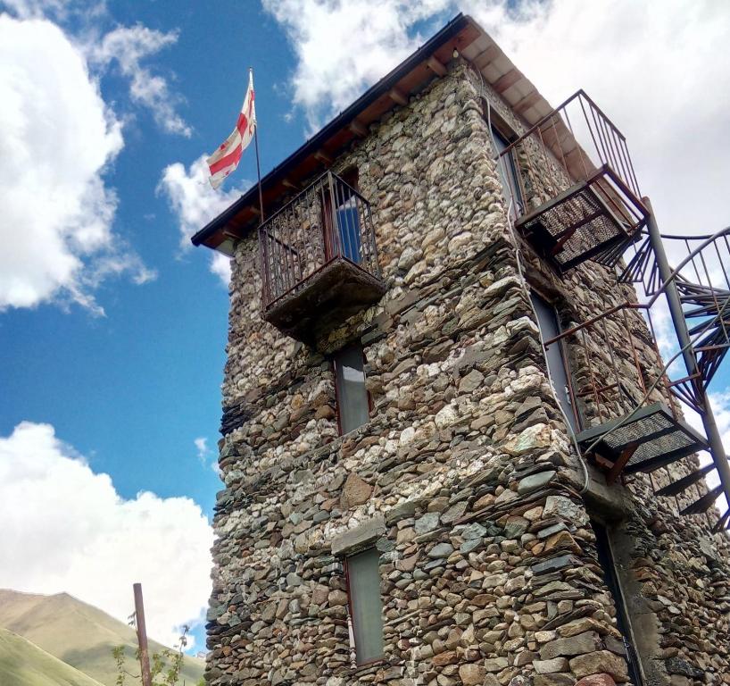 un edificio de piedra con balcón y bandera en Hotel Veshagi, en Juta