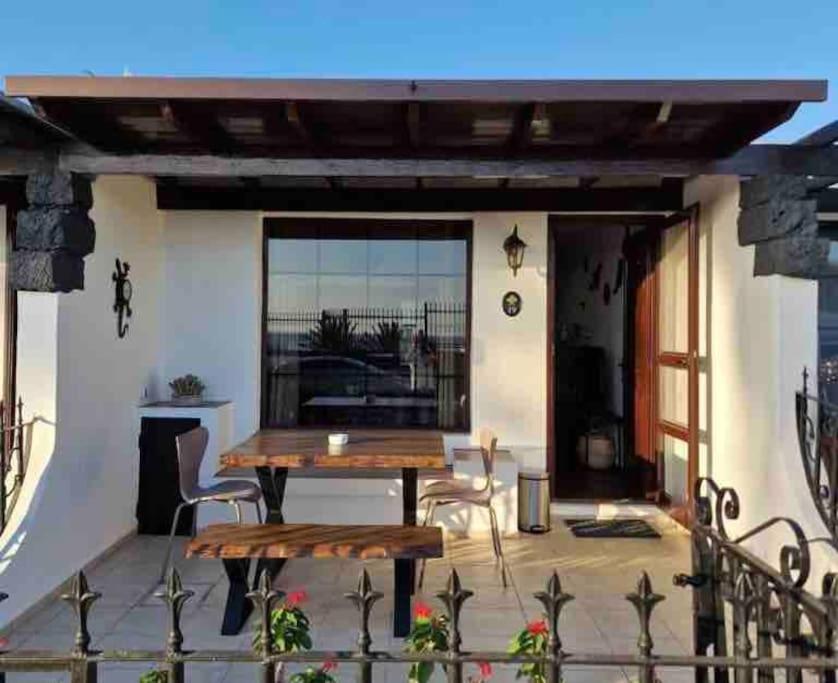 eine Terrasse mit einem Holztisch und Stühlen in der Unterkunft Apartamento Los Marinos in Tías