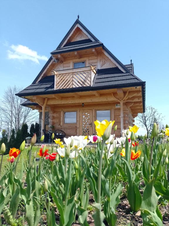 a log cabin with flowers in front of it at Domek Na Góralską Mode in Suche