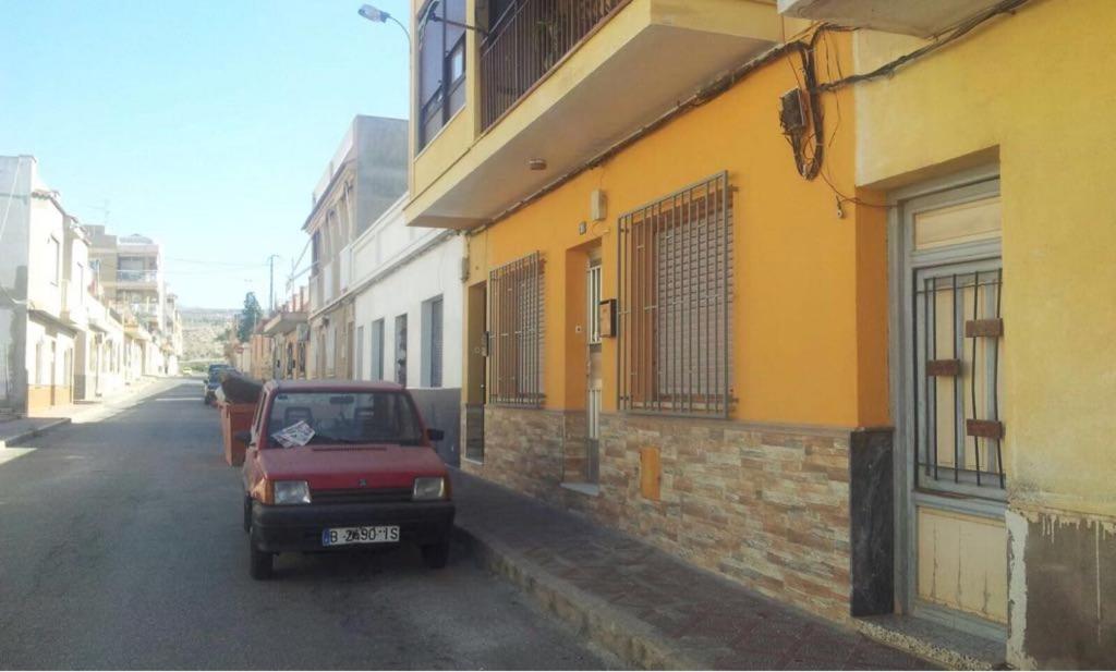 ein rotes Auto, das auf einer Straße neben einem Gebäude parkt in der Unterkunft Planta Baja En Águilas 3 dormitorios in Águilas