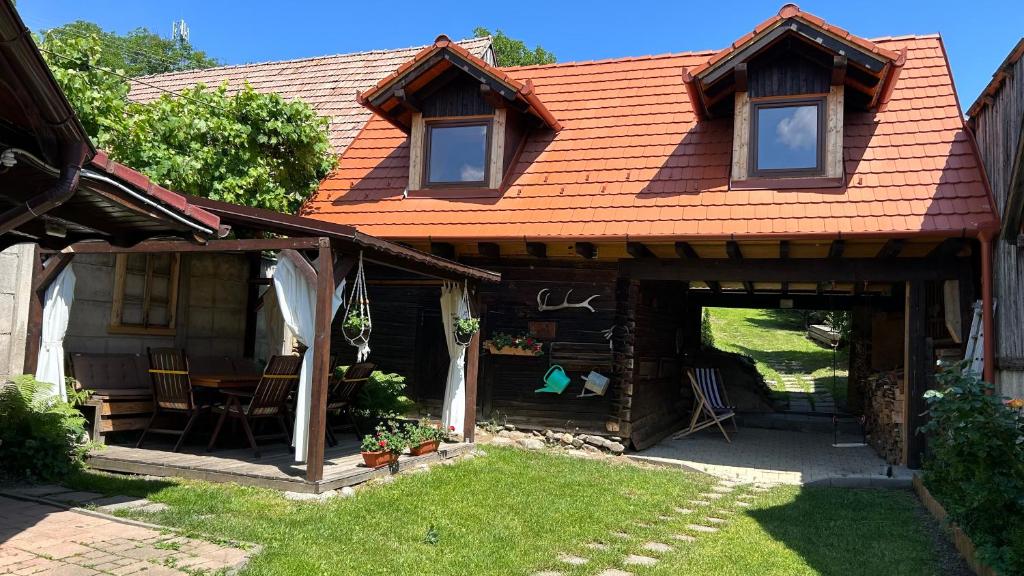 ein Haus mit einem orangenen Dach und einer Terrasse in der Unterkunft Casa veche “Old house” in Sibiel