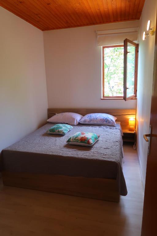 a bedroom with a bed with two pillows and a window at Apartments Sunset Jadranovo in Jadranovo