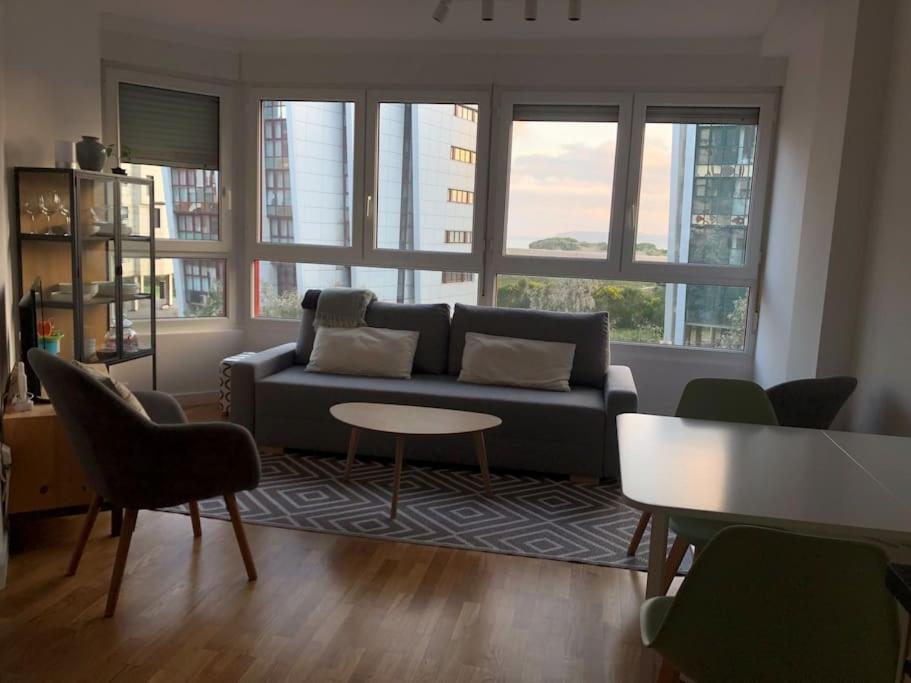 a living room with a couch and a table and windows at A Estrenar. Apartamento Reformado con vistas. in Salinas