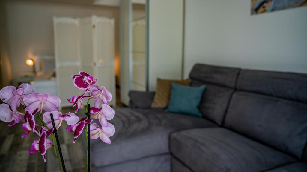 a vase with purple flowers in front of a couch at Apartments Edera in Tivat