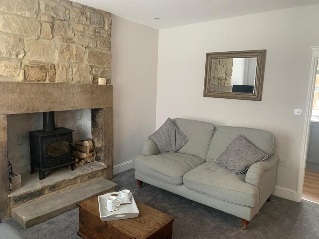 sala de estar con sofá y chimenea en Tipsy Cottage Charming 2 bedroom home. en Burley in Wharfedale