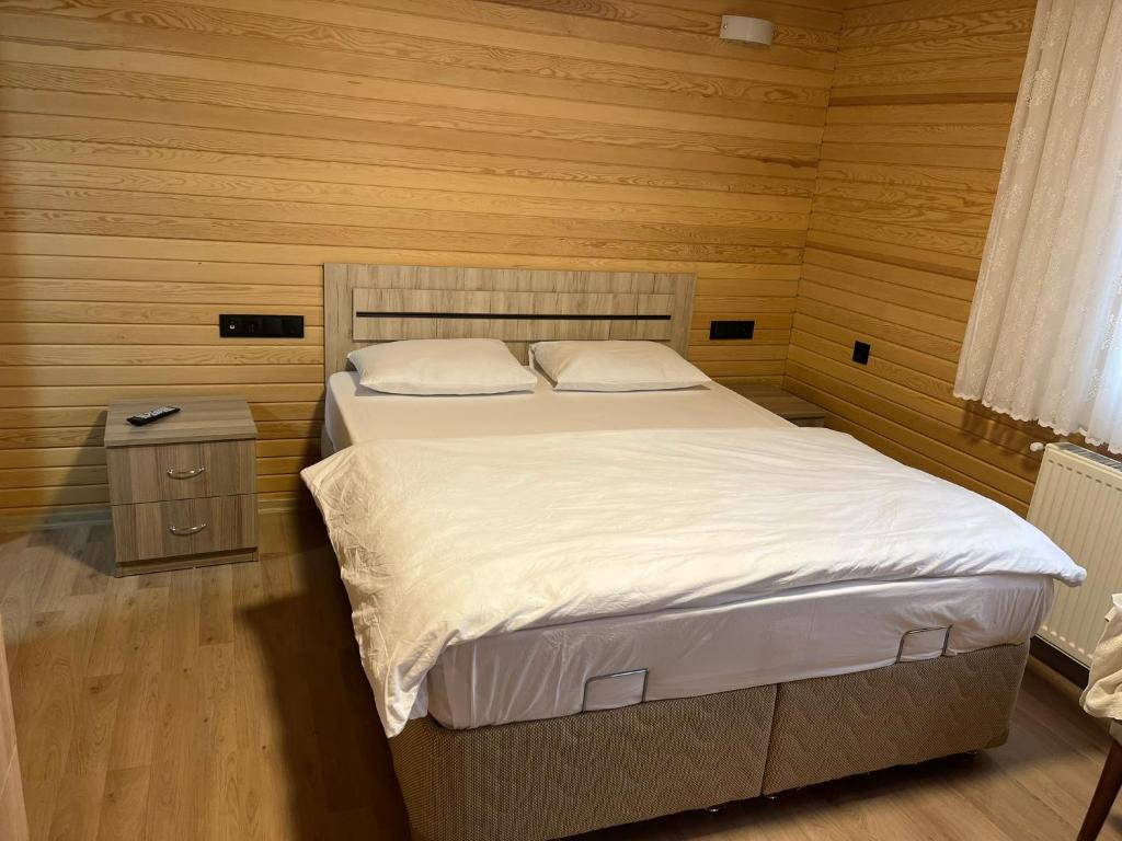 een slaapkamer met een bed en een houten muur bij ESPİRA APART in Çaykara