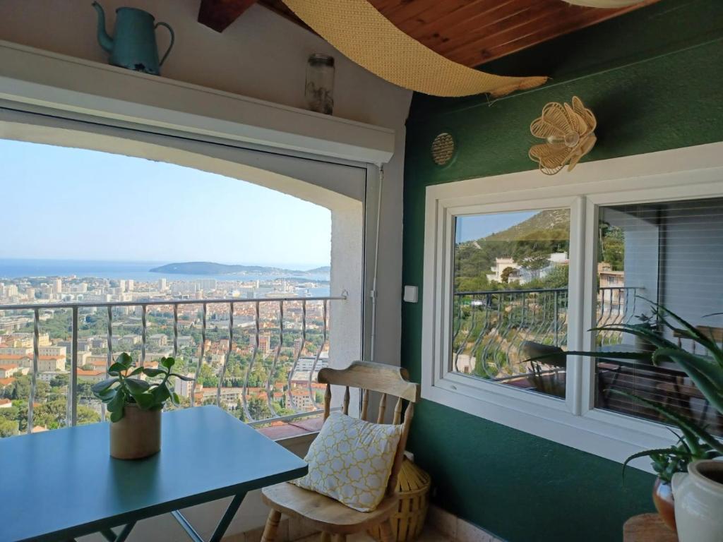 une table et une chaise dans une pièce avec une fenêtre dans l'établissement Le Balcon, vue panoramique au Faron, à Toulon