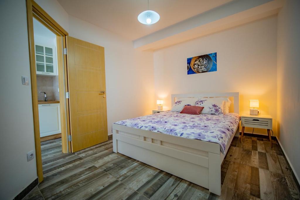 a bedroom with a bed and two lamps and a door at Apartments Edera in Tivat