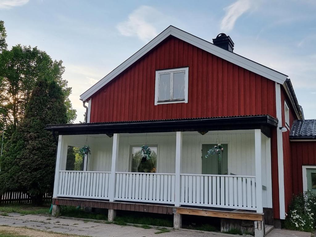 une maison rouge et blanche avec une véranda blanche dans l'établissement Gamla Kooperativa, à Ekshärad