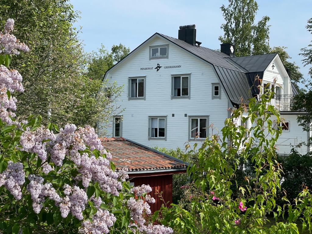 a white house with flowers in front of it at Pensionat Grisslehamn in Grisslehamn