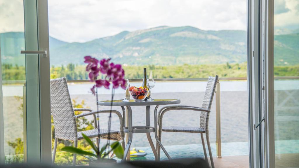a table and chairs on a balcony with a view of the mountains at Apartments Edera in Tivat