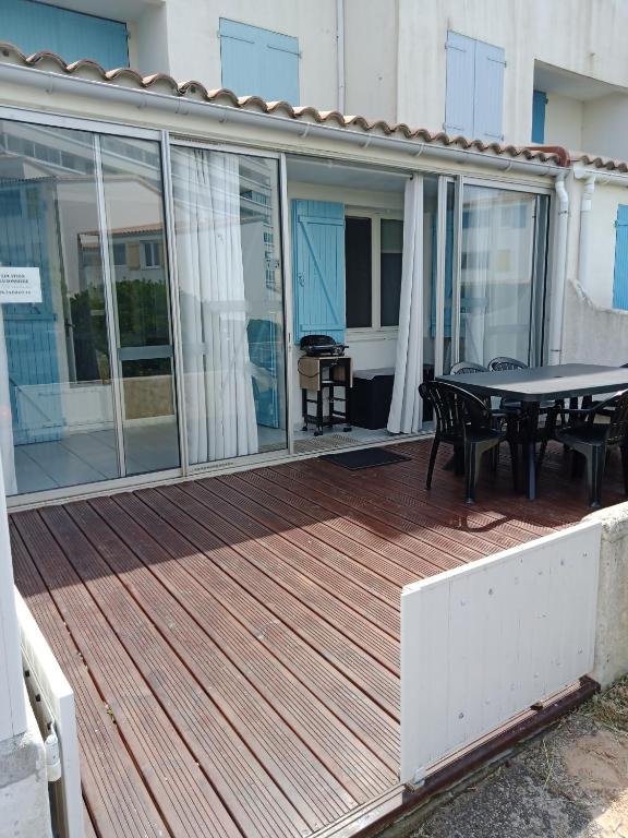 une terrasse avec une table et des chaises. dans l'établissement APPARTEMENT BORD DE MER, à Saint-Hilaire-de-Riez