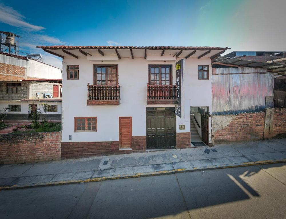 ein weißes Haus mit Fenstern und einer Tür auf einer Straße in der Unterkunft Hostal La Morada in Chachapoyas