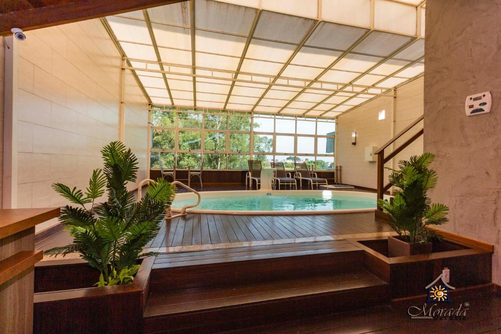 une grande piscine intérieure avec une grande fenêtre dans l'établissement Hotel Morada Del Este, à Canoas