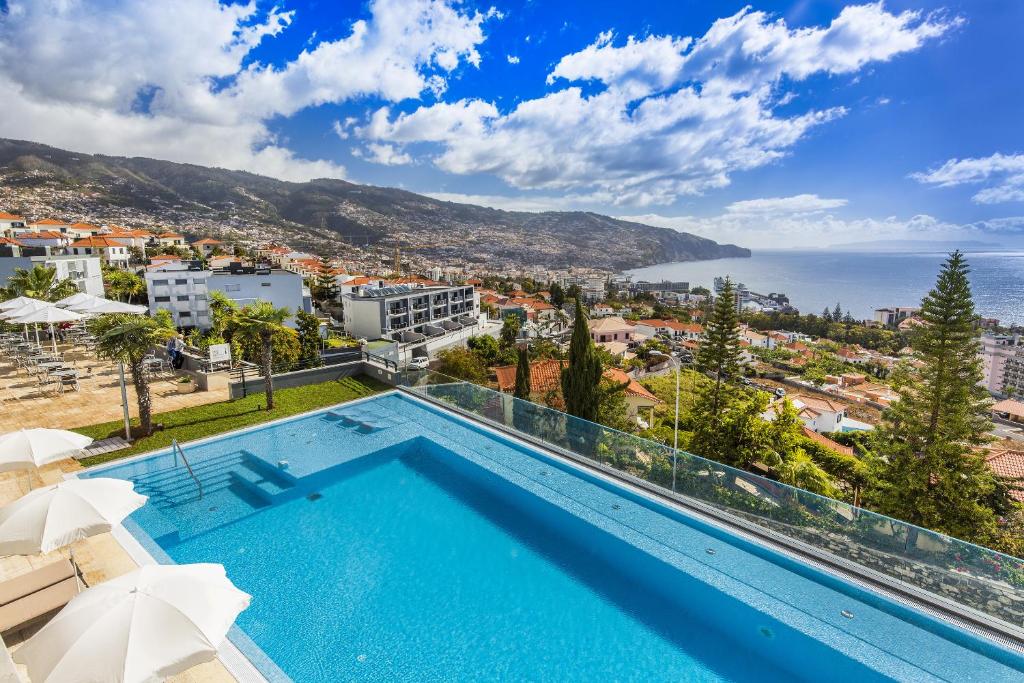uma piscina com vista para a cidade e para o oceano em Madeira Panorâmico Hotel no Funchal
