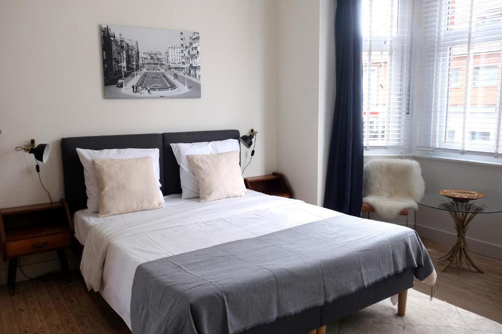 a bedroom with a bed with white sheets and a window at Villa Bérylune in Ostend