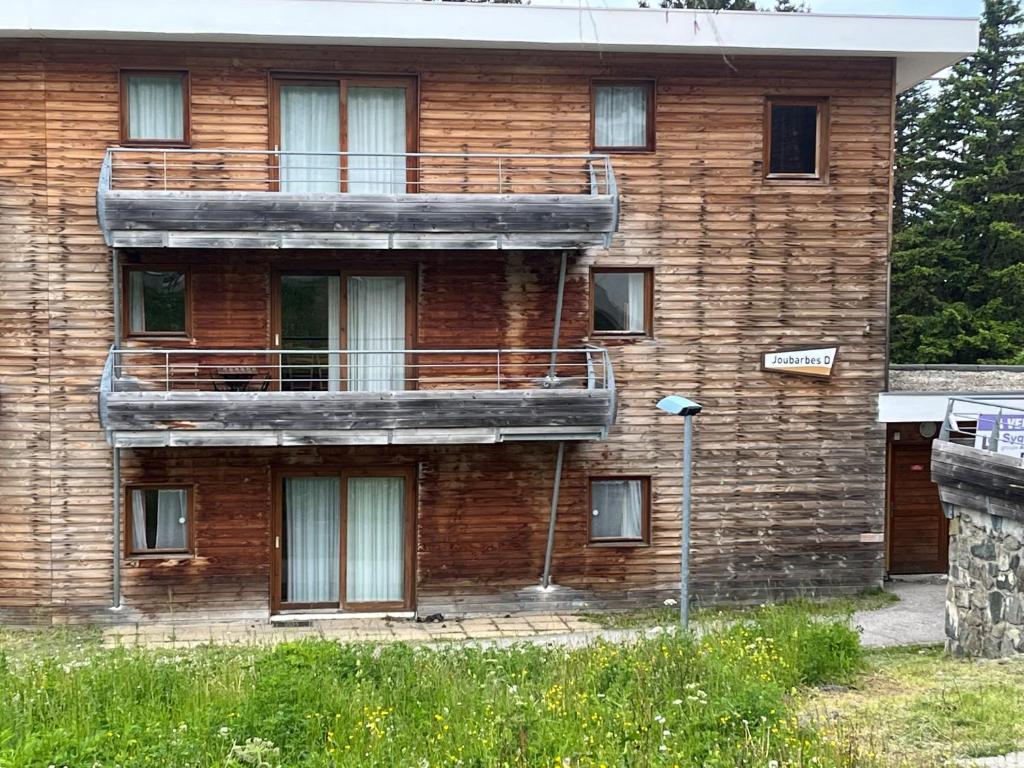 ein Holzgebäude mit einem seitlichen Balkon in der Unterkunft Chamrousse Appart 8 personnes au pied des pistes in Chamrousse
