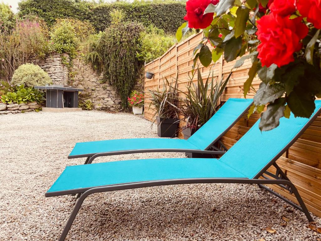 a blue lounge chair in a garden with red roses at Sur le chemin de la plage in Cherbourg en Cotentin