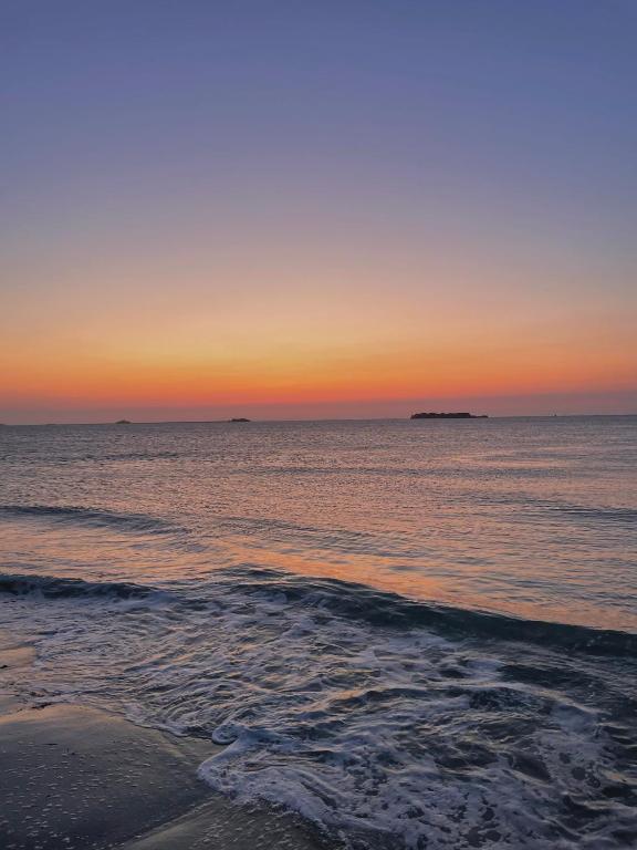 a sunset over the ocean with a beach at Sur le chemin de la plage in Cherbourg en Cotentin