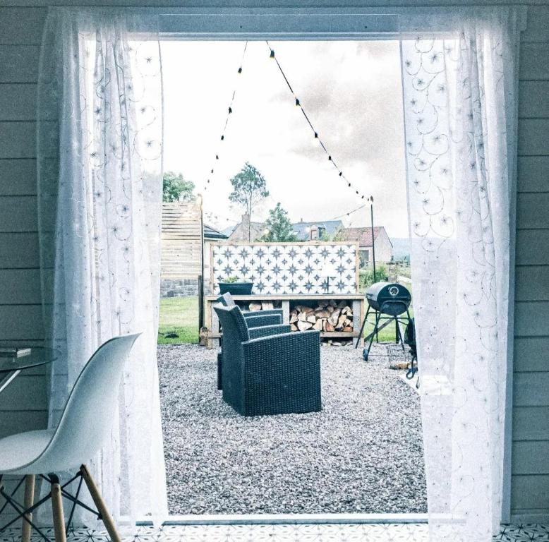 Blick auf eine Terrasse durch ein Fenster in der Unterkunft The Wee Stay - Rural Guest Suite with outdoors Kitchen and covered Livingroom area in Crook of Devon