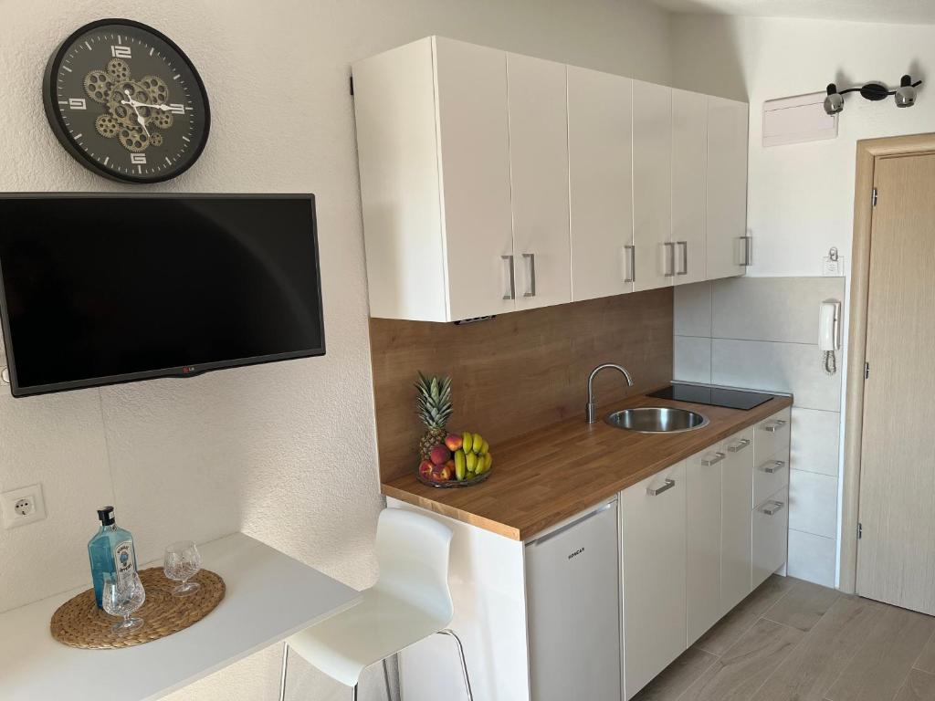 a kitchen with white cabinets and a clock on the wall at Apartments Nela in Podstrana